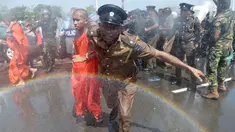 Seorang polisi mengamankan biksu saat aksi protes di kota pelabuhan selatan Hambantota, Sri Lanka (7/1). Mereka memprotes pembuatan zona industri untuk investasi China di sebuah kawasan di Sri Lanka. (AFP/ Ishara S. Kodikara)