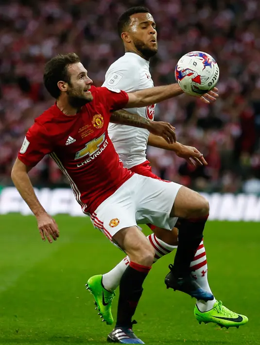 Gelandang Manchester United, Juan Mata berebut bola dengan bek Southampton, Ryan Bertrand pada final Piala Liga Inggris di Stadion Wembley, London, (27/2). MU menang atas Southampton dengan skor 3-2. (AFP Photo / Ian Kington)
