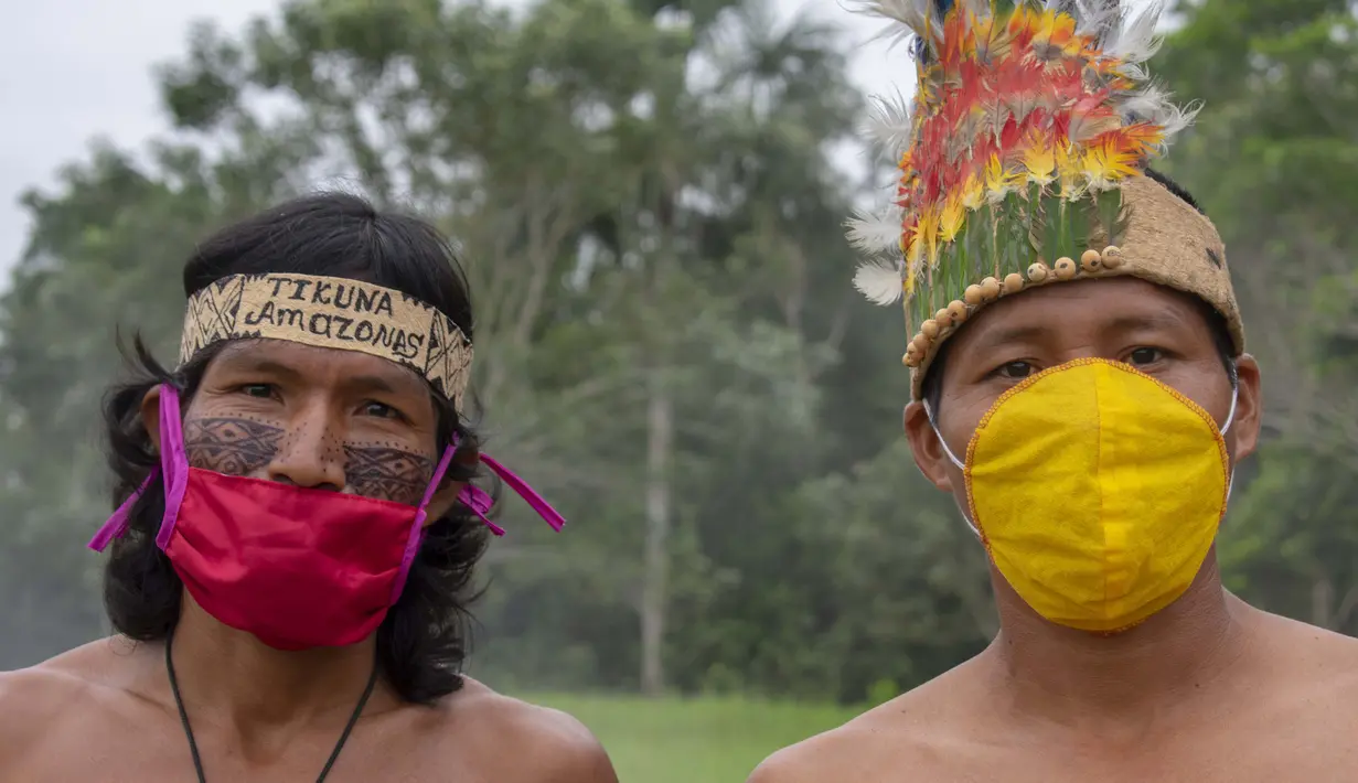 Suku Tikuna berpose mengenakan masker di tengah kekhawatiran virus corona Covid-19 di Leticia, Departemen Amazonas, Kolombia pada 8 Juni 2020. Kasus virus corona ini meningkatkan kekhawatiran akan resiko penyebaran ke masyarakat adat yang rentan dan berada di pedalaman. (Tatiana de NEVO/AFP)