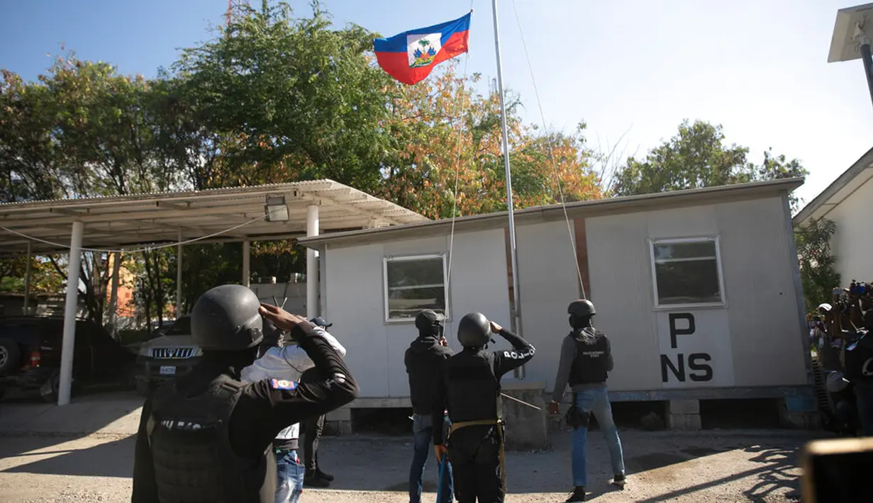 Petugas polisi memberi hormat kepada bendera Haiti setengah tiang dalam kompleks markas polisi saat protes untuk mengecam tata kelola polisi yang buruk di Port-au-Prince, Haiti, 26 Januari 2023. Port-au-Prince dan sejumlah kota lain telah dilanda kekhawatiran selama berbulan-bulan terakhir menyusul meningkatnya perang yang mematikan antar geng. (AP Photo/Odelyn Joseph)