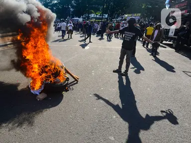 Massa membakar poster dan ban bekas saat aksi terkait putusan sengketa Pilpres di MK, di kawasan bundaran Patung Kuda, Jakarta, Senin (22/4/2024). (merdeka.com/Arie Basuki)