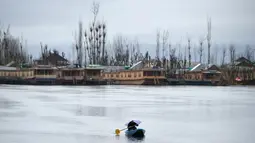 Seorang awak perahu Kashmir memegang payung saat hujan di Danau Dal di Srinagar (20/3). Danau terbesar kedua di propinsi Jammu dan Kashmir ini  merupakan pusat pariwisata dan rekreasi. (AFP Photo/Tauseef Mustafa)