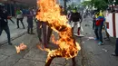 Sejumlah demosntran bereaksi saat rekannya terbakar pada unjuk rasa yang diwarnai bentrokan menentang Presiden Venezuela, Nicolas Maduro di Caracas, Rabu (3/5). Pria itu tersulut api dari ledakan tangki sepeda motor milik polisi. (RONALDO SCHEMIDT / AFP)