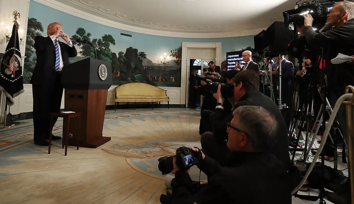 Presiden AS Donald Trump meminum air dari botol mineral disela menyampaikan pidato di Ruang Diplomatik Gedung Putih, Rabu (15/11). Diketahui, Trump pernah mengejek senator AS Marco Rubio yang minum saat sedang berpidato pada 2013 lalu. (NICHOLAS KAMM/AFP)