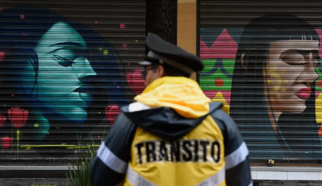 Polisi lalu lintas berdiri di depan toko yang dihiasi mural sebagai bagian dari program pemerintah di Mexico City, 30 Agustus 2017. Mural  sebagai bagian dari upaya pemerintah menghidupkan kembali ruang publik di wilayah kota tua. (ALFREDO ESTRELLA/AFP)