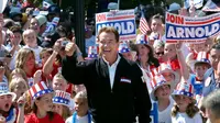 Pada 5 Oktober 2003, kandidat Partai Republik gubernur California Arnold Schwarzenegger berjalan menaiki tangga ke negara bagian Capitol dikelilingi oleh anak-anak dan melambai kepada pendukung selama kampanye di Sacramento, California. (Steve Yeater/AP Photo)