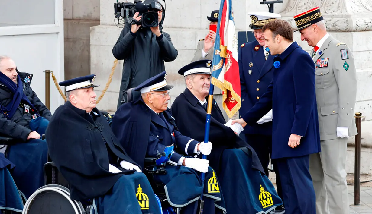 Presiden Prancis Emmanuel Macron (kedua kanan)menyapa para veteran di Arc de Triomphe, Paris, Prancis, 11 November 2022. Upacara ini digelar untuk menandai peringatan 104 tahun Gencatan Senjata 11 November 1918 yang mengakhiri Perang Dunia I. (Ludovic Marin, Pool via AP)