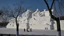 Orang-orang berjalan di samping patung salju raksasa di Pameran Seni Patung Salju Internasional Harbin Sun Island menjelang Festival Es dan Salju Internasional Harbin Tiongkok ke-39 di Harbin, di provinsi Heilongjiang timur laut China (4/1/2023). (AFP/Hector Retamal)