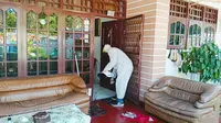 Personel Polsek Tampan masuk ke rumah warga terkonfirmasi Covid-19 menyemprotkan disinfektan. (Liputan6.com/M Syukur)