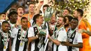 Pemain Juventus, Paulo Dybala dan Miralem Pjanic mengangkat trofi Piala Super Italia 2018 seusai mengalahkan AC Milan pada laga final di King Abdullah Sports City, Kamis (17/1). Juventus keluar sebagai kampiun dengan meraih kemenangan tipis 1-0 (AP Photo)