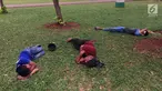 Sejumlah pengunjung bersantai sambil tiduran di sekitar Taman Monas, Jakarta, Rabu (17/1). Dibukanya pagar pembatas Taman Monas membuat warga bisa masuk ke area taman yang mengelilingi lokasi wisata di Ibu Kota tersebut. (Liputan6.com/Immanuel Antonius)