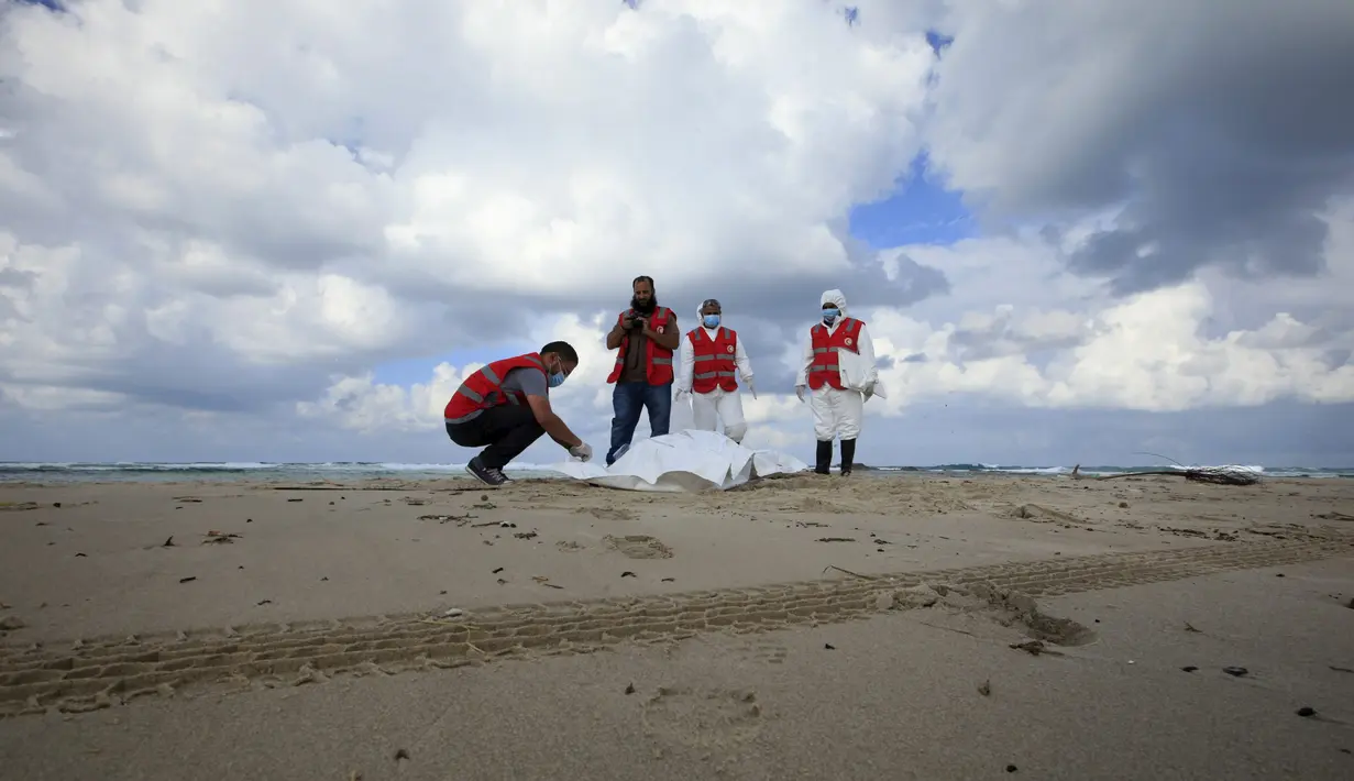 Kelompok Bulan Sabit Merah Libya memeriksa jenazah, diduga imigran  yang tewas usai kapal mereka tenggelam, di pantai Khoms, sebelah timur Tripoli, Minggu (25/10). Sedikitnya 40 jasad telah ditemukan di pantai Libya. (REUTERS/Ismail Zitouny)
