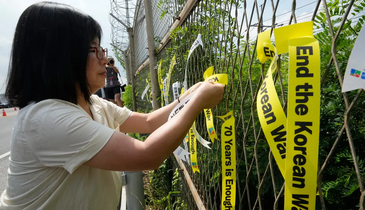 Seorang aktivis antiperang menggantungkan pita yang mengharapkan reunifikasi kedua Korea di pagar kawat selama rapat umum memperingati 70 tahun Perjanjian Gencatan Senjata Perang Korea dekat Jembatan Unifikasi yang mengarah ke Panmunjom di Zona Demiliterisasi, Paju, Korea Selatan, Kamis (27/7/2023). (AP Photo/Ahn Young-joon)