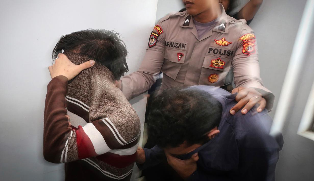 Petugas kepolisian mengawal dua orang terdakwa pasangan sejenis (gay) untuk menjalani persidangan di pengadilan syariah di Banda Aceh (17/5). Majelis hakim Mahkamah Syar'iyah Banda Aceh memvonis terdakwa dengan 85 kali cambuk. (AP Photo/Heri Juanda)