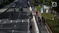 Sejumlah pesepeda melintasi jalur kendaraan bermotor saat uji coba pembatas jalur sepeda permanen di kawasan Sudirman, Jakarta, Minggu (28/2/2021). Uji coba berlangsung selama tahap penyempurnaan jalur sepeda permanen yang ditargetkan rampung akhir Maret 2021. (Liputan6.com/Johan Tallo)