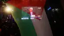Warga Palestina mengibarkan bendera mereka saat menonton pidato Presiden Palestina, Mahmud Abbas di layar raksasa, Rabu (30/9). Sidang majelis Umum PBB menyetujui untuk mengibarkan bendera Palestina dan Vatikan. (AFP PHOTO/Jaafar ASHTIYEH)