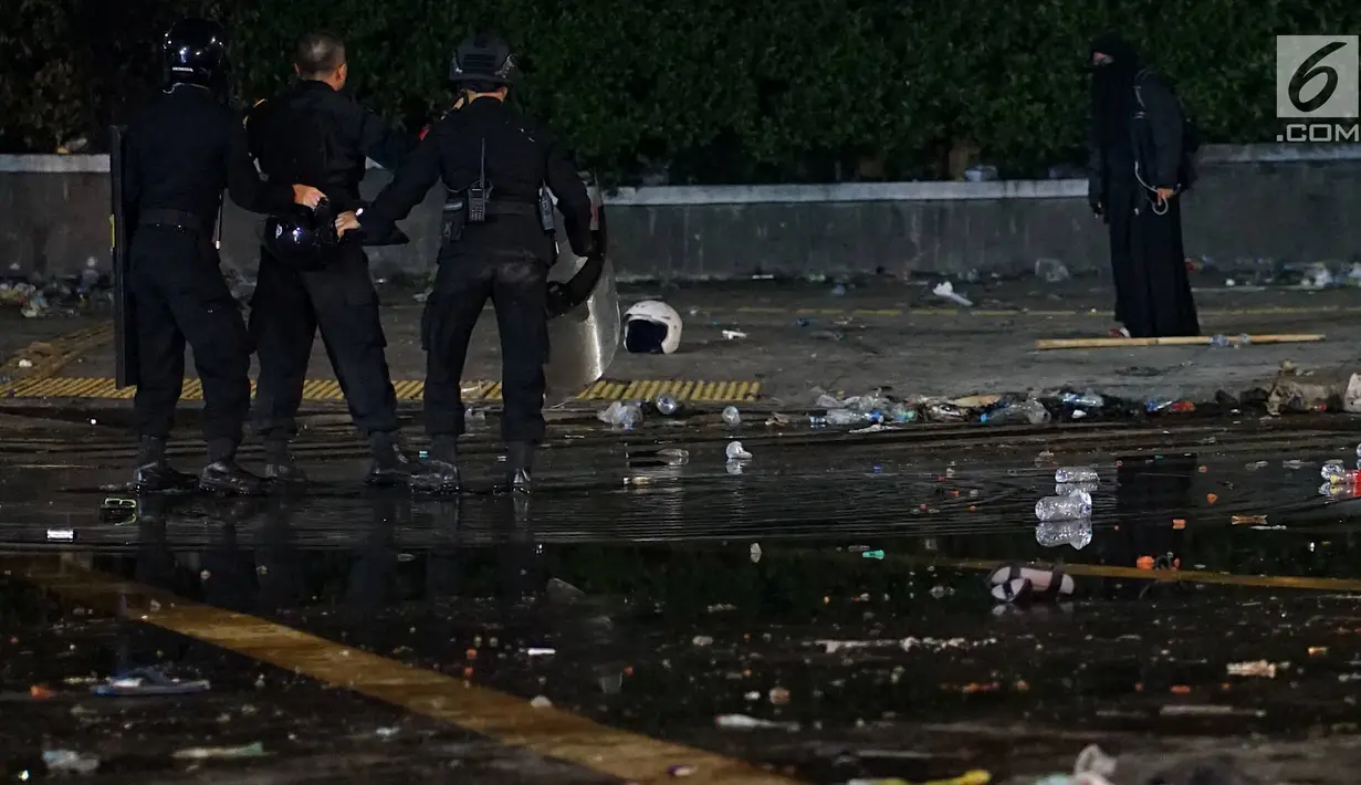 Aparat kepolisian dari Satuan Brimob berusaha menahan perempuan bercadar hitam dengan kabel menjuntai di tangan berusaha mendekat Gedung Bawaslu, Jakarta, Rabu (22/5/2019). Perempuan misterius yang berjalan sendiri tanpa massa ini mengenakan baju gamis warna hitam. (Liputan6.com/Immanuel Antonius)