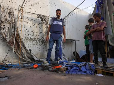 Anak-anak Palestina dan seorang jurnalis memeriksa tenda Al Jazeera yang hancur di Rumah Sakit Al-Shifa di Kota Gaza pada 11 Agustus 2025, menyusul serangan semalam oleh militer Israel. (BASHAR TALEB/AFP)