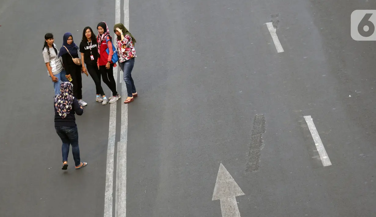 Warga memanfaatkan kondisi lengang sebagian ruas jalan Jenderal Sudirman untuk berfoto, Jakarta, Minggu (27/10/2019). Sebagian ruas Jalan Jenderal Sudirman dialihkan akibat  berlangsungnya Karnaval Kendaraan Listrik yang bertajuk Jakarta Langit Biru. (Liputan6.com/Helmi Fithriansyah)