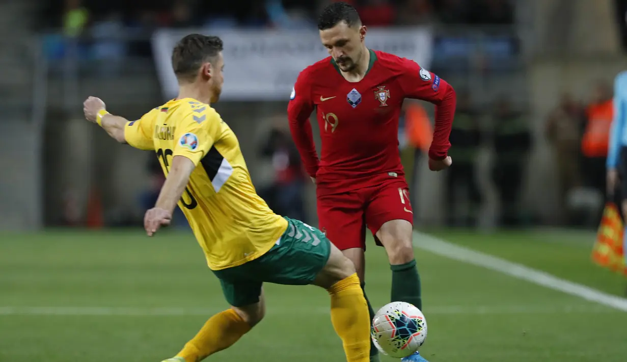 Bek Portugal, Mario Rui berusaha melewati pemain Lithuania, Saulius Mikoliunas pada pertandingan Grup B Kualifikasi Piala Eropa 2020 di stadion Algarve di luar Faro, Portugal (14/11/2019). Portugal menang besar 6-0 atas Lithuania. (AP Photo/Armando Franca)