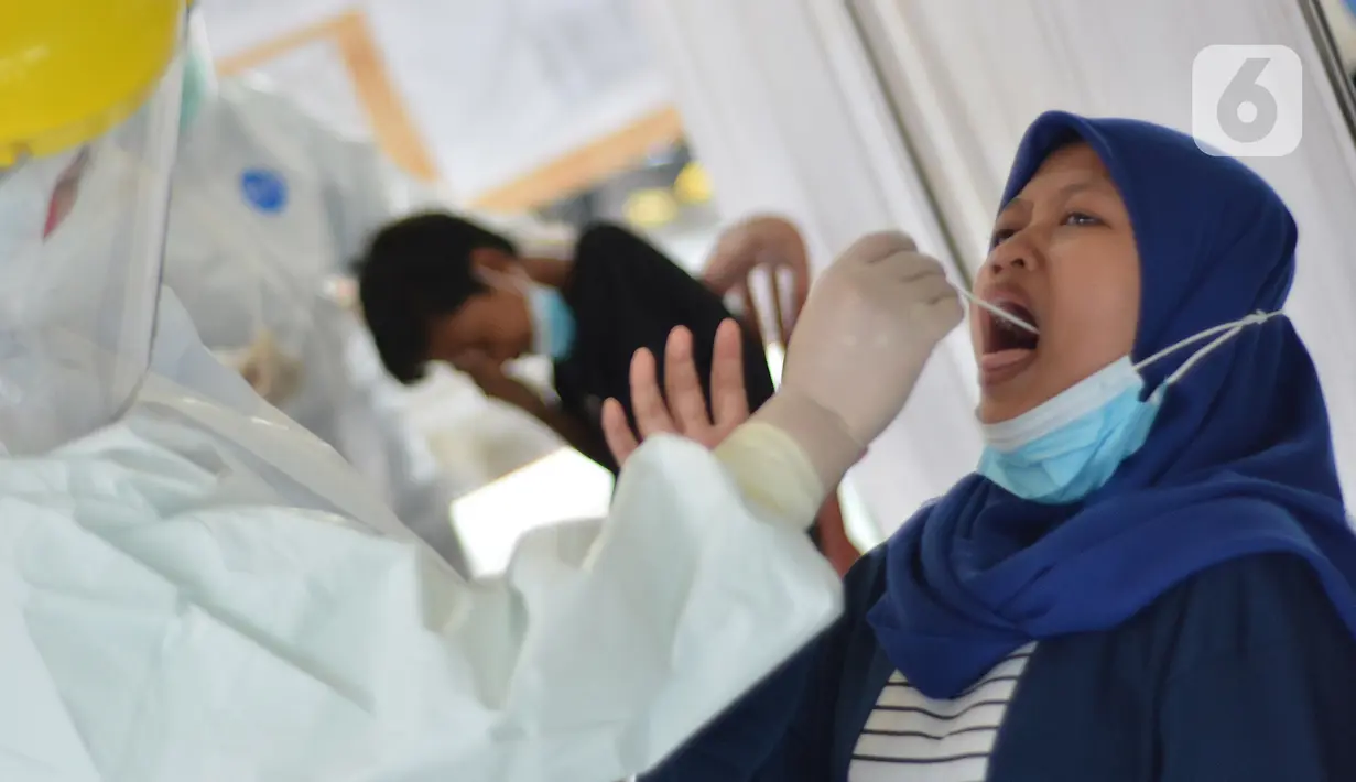 Petugas medis mengambil sampel lendir saat tes swab PCR massal di Kantor Kecamatan Pancoran Mas, Depok, Selasa (5/1/2021). Puskesmas Pancoran Mas melakukan tes Swab PCR kepada warga yang pernah memiliki riwayat kontak erat dengan pasien terkonfirmasi positif Covid-19. (merdeka.com/Arie Basuki)