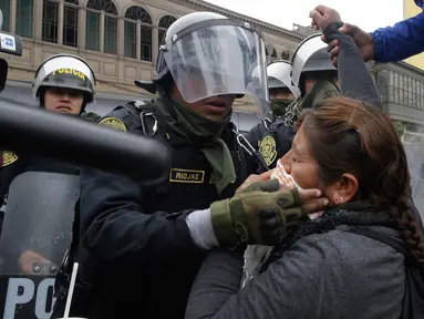 Petugas polisi membantu seorang guru yang terkena gas air mata saat unjuk rasa di Lima, Peru,  (24/8). Sejumlah  Guru sekolah umum menuntut kenaikan gaji. (AP Photo / Martin Mejia)