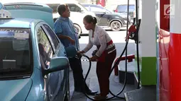 Petugas dengan pakaian adat mengisi bahan bakar minyak (BBM) ke sebuah taksi di SPBU, Bali, Rabu (10/10). Petugas SPBU mengenakan pakaian adat Bali untuk menyambut pertemuan tahunan IMF dan Bank Dunia. (Liputan6.com/Angga Yuniar)