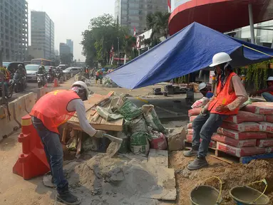 Pekerja menyelesaikan proyek pembangunan trotoar di Jalan MH Thamrin,Jakarta,Kamis (19/7). Jelang Asian Games 2018, pengerjaan infrastruktur di Jakarta terus dikebut. (Merdeka.com/Imam Buhori)