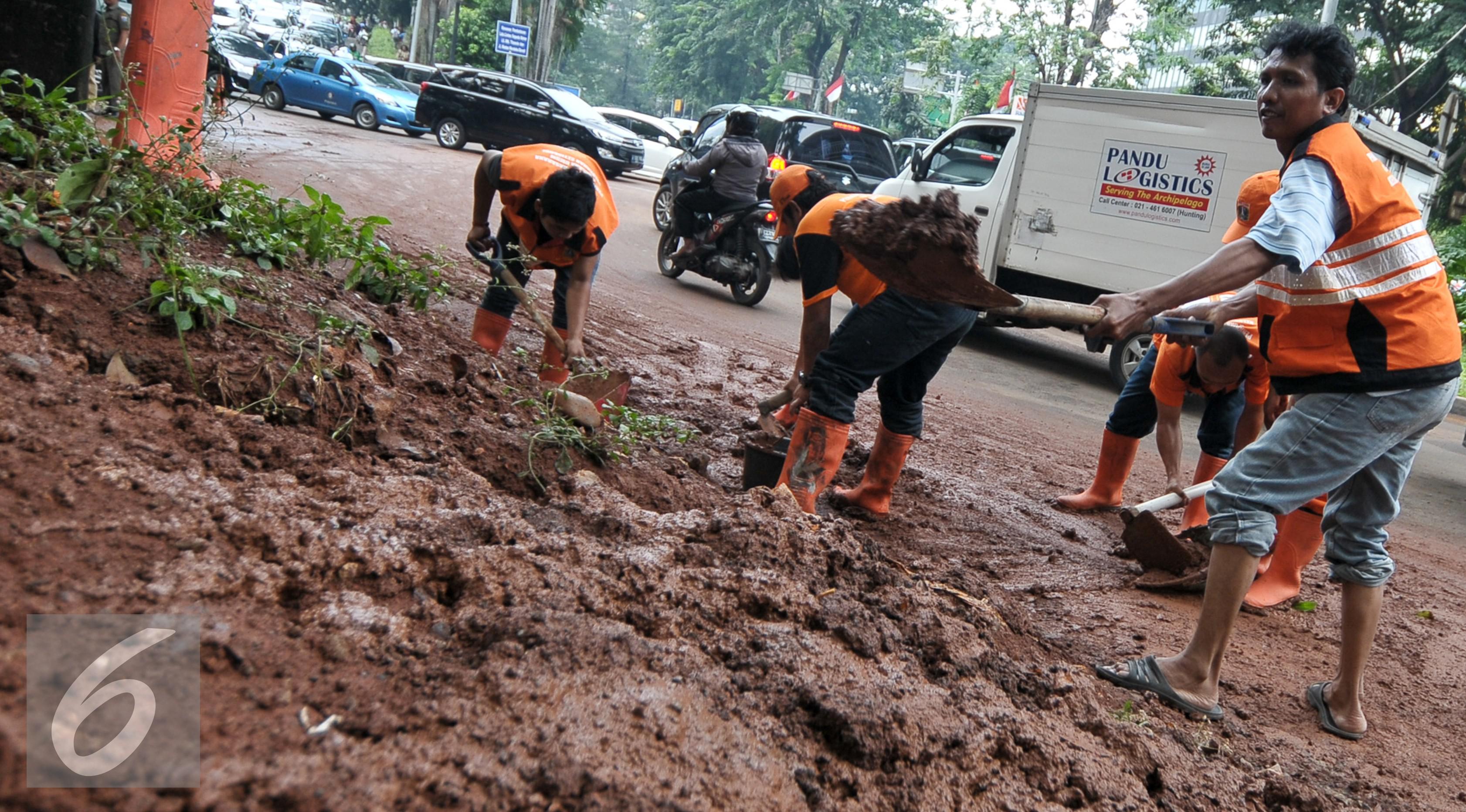 Petugas PPSU atau yang lebih dikenal dengan sebutan Pasukan Oranye membersihkan sendimen tanah merah yang longsor ke jalan Galunggung, Jakarta, Selasa (30/8/2016). (Liputan6.com/Yoppy Renato)
