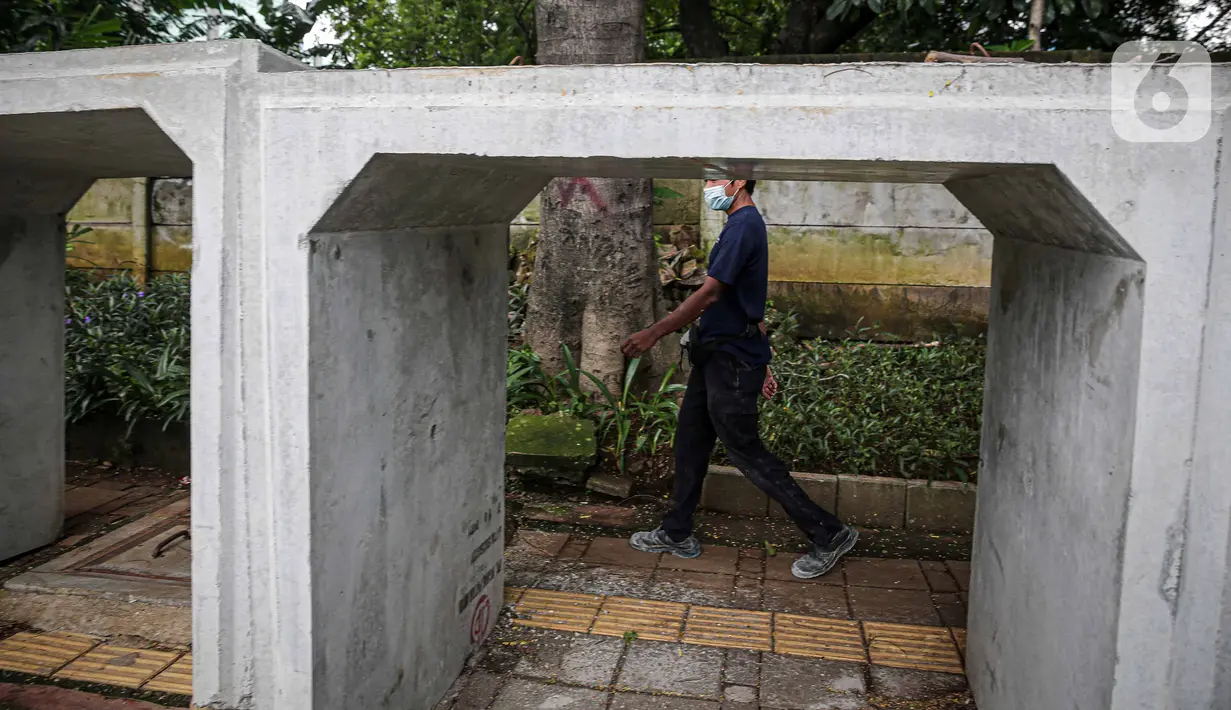 Pejalan kaki melintas di samping beton saluaran air yang berada di jalur pedestrian kawasan Gatot Subroto, Jakarta, Selasa (21/12/2021). Selain mengganggu kenyamanan, keberadaan beton saluran air tersebut juga dapat membahayakan pejalan kaki yang melintas. (Liputan6.com/Faizal Fanani)