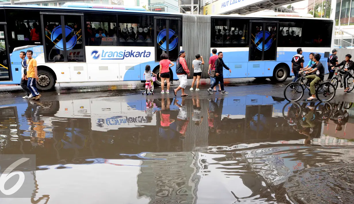 Kegiatan Car Free Day di Jakarta tetap ramai walau hujan mengguyur sejak semalam, Minggu (24/1/2016). Sebuah Busway melintas di jalan sekitar kawasan Car Free Day. (Liputan6.com/Helmi Affandi)