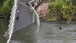 Tim penyelamat menyelam di  sungai Tarm, dekat jembatan gantung yang ambruk di Prancis, Selasa (18/11/2019). Satu mobil dan satu truk dan kemungkinan sebuah kendaraan lainnya yang sedang melintasi jembatan itu langsung hanyut ke sungai. (ERIC CABANIS/AFP)