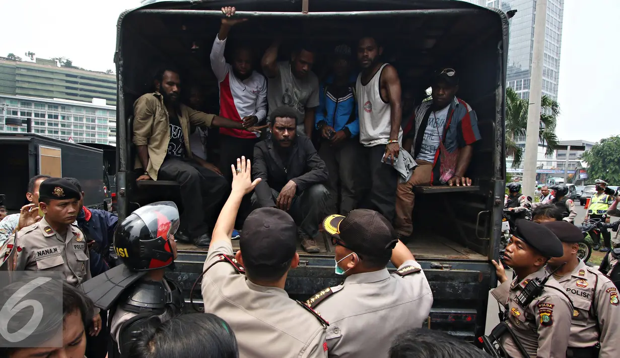Mahasiswa Papua berada di dalam mobil petugas usai berunjuk rasa di kawasan Bunderan HI, Jakarta, Selasa (1/12). Massa menyerahkan diri sebagai bentuk solidaritas usai puluhan lainnya diamankan petugas pascabentrok. (Liputan6.com/Immanuel Antonius)