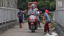 Pengendara motor melintas di samping anak-anak yang bermain di Jembatan Penyeberangan Orang kawasan Cikunir, Bekasi Barat, Senin (12/3). JPO untuk bagi pejalan kaki ini justru digunakan pemotor mencari jalan pintas. (Liputan6.com/Arya Manggala)