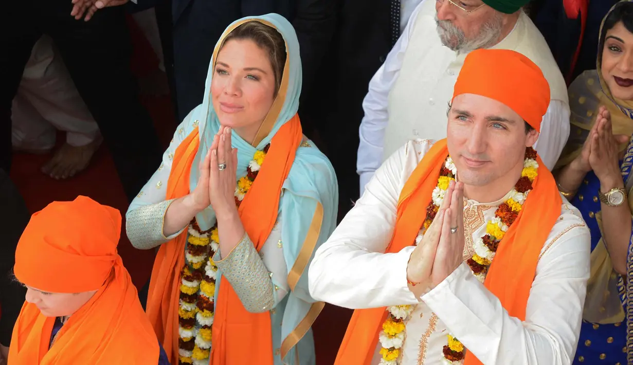 Perdana Menteri Kanada Justin Trudeau (kanan) bersama istrinya Sophie Gregoire (kiri) memberi penghormatan di Kuil Emas Sikh di Amritsar, India (21/2). Trudeau dan istri memakai busana khas India saat mengunjungi kuil tersebut. (AFP Photo/Narinder Nanu)