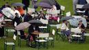 Para tamu berlindung di bawah payung dari hujan saat mereka duduk di meja saat menghadiri pesta kebun pertama musim ini di Istana Buckingham, London, Inggris, 11 Mei 2022. Pesta kembali untuk pertama kalinya sejak 2019 setelah wabah virus corona COVID-19. (AP Photo/Matt Dunham, Pool)