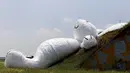 Kelinci raksasa bernama "Moon Rabbit" ini ditampilkan di atas sebuah hanggar pesawat tua dalam Taoyuan Land Art Festival yang dihelat di pangkalan militer, Taiwan, (3/9/2014). (REUTERS/Pichi Chuang)