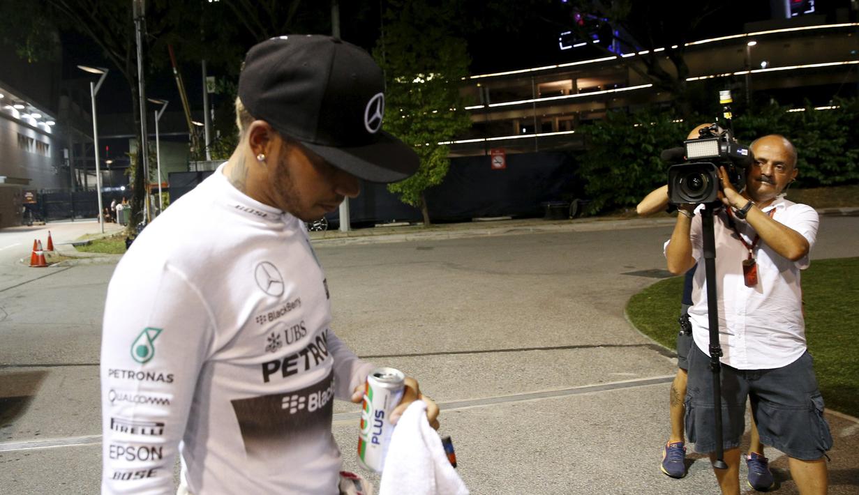 Pebalap Mercedes, Lewis Hamilton, berjalan di paddock setelah mobilnya mengalami kerusakan di GP Singapura. Minggu (20/9/2015). (Reuters/Edgar Su)
