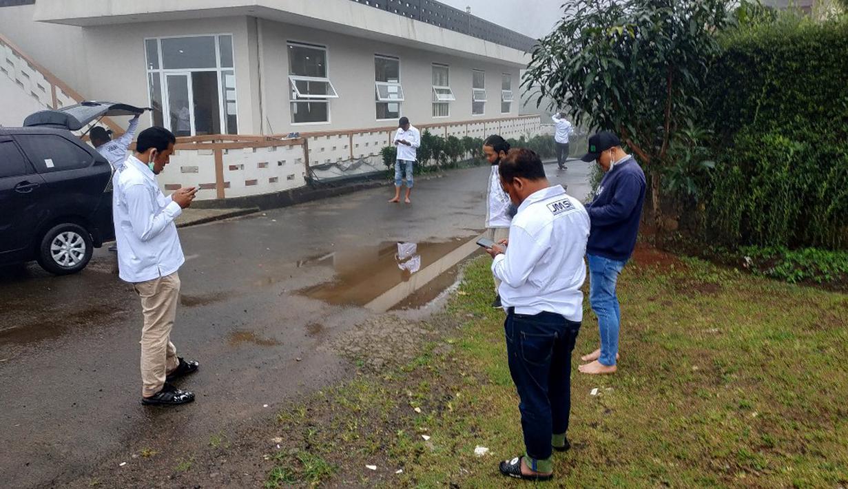 Warga memeriksa ponsel mereka saat berkumpul di luar bangunan tak lama setelah gempa mengguncang Cisarua, Bogor, Jawa Barat, Jumat (14/1/2022). Gempa magnitudo 6,7 yang berpusat di Banten pada pukul 16.05 WIB membuat kepanikan di berbagai daerah. (FAJRIN RAHARJO/AFP)