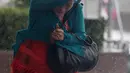Warga berlindung di balik payung untuk menghindari angin kencang yang disebabkan topan Dujuan di Taipei, Taiwan, Senin (28/9). Ribuan orang diungsikan untuk menghadapi topan raksasa Dujuan yang diprediksikan akan menyerang Taiwan. (REUTERS/Pichi Chuang)