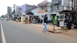 Pejalan kaki melintasi lubang bekas galian yang ditanami pohon pisang di pinggir Jalan Raya Margonda, Depok, Senin (4/3/2019). Aksi tanam pohon pisang itu sebagai protes warga akibat banyaknya lubang galian di Jalan Margonda (Liputan6.com/Herman Zakharia)