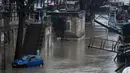 Sebuah mobil melintasi banjir di tepi sungai Seine, Paris (22/1). Sungai Seine telah berubah menjadi torrent berlumpur yang kuat yang telah menenggelamkan taman dan jalan. (AFP Photo/Stephane De Sakutin)