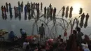 Umat Hindu India berdoa kepada matahari selama Festival Chhath di tepi Danau Hussain Sagar, Hyderabad, Selasa (13/11). Festival Hindu kuno ini dilakukan sebagai bentuk terima kasih kepada Dewa Matahari yang menopang kehidupan di bumi. (NOAH SEELAM / AFP)