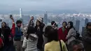 Wisatawan mengambil gambar di Peak di Hong Kong pada 26 Desember 2015 (atas) dan seorang pria mengenakan masker sebagai tindakan pencegahan terhadap penyebaran virus corona (COVID-19) di lokasi yang sama pada 7 Maret 2020. (DALE de la REY, Vivek PRAKASH/AFP)