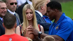Ivanka Trump belajar melempar bola dari Herschel Walker selama acara White House Sports and Fitness Day" di Gedung Putih, Washington, AS, (30/5). Ivanka tampil cantik dengan rambut diurai saat belajar bermain rugby. (AP Photo / Susan Walsh)