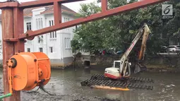 Alat berat digunakan untuk mengeruk lumpur dan sampah yang mengendap di anak Sungai Ciliwung, Jakarta, Jumat (26/1). Selain itu, pengerukan juga dilakukan mengantisipasi banjir seiring datangnya musim hujan. (Liputan6.com/Immanuel Antonius)