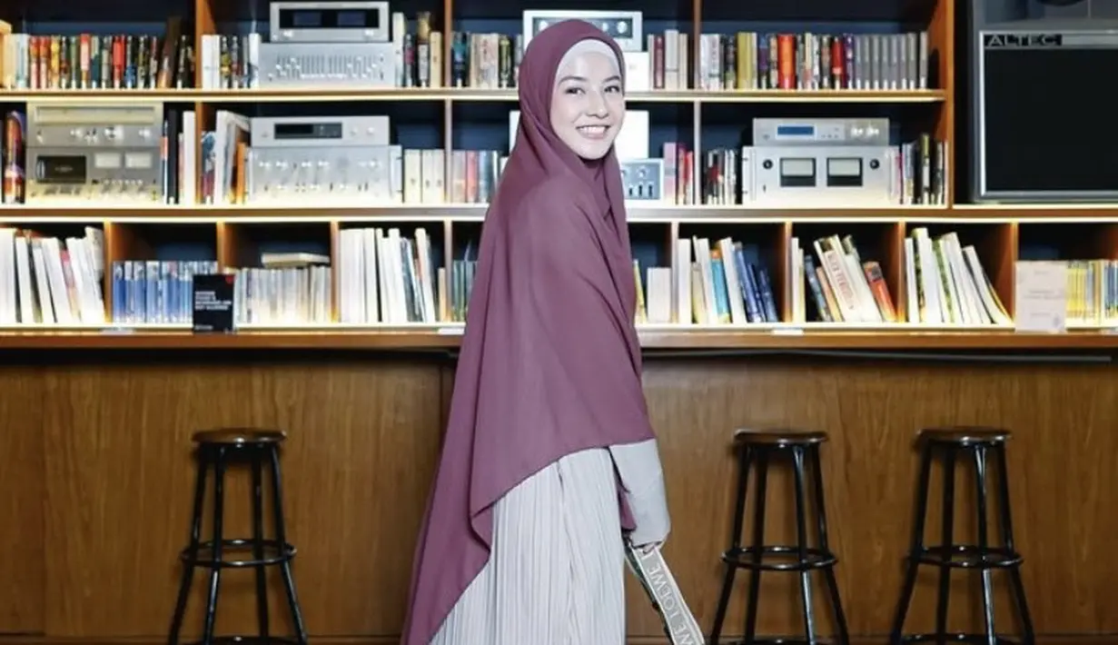 Dress plisket warna coffe latte dipadukan kerudung maroon. Serta membawa sling bag coklat dan sandal putih. [@natasharizkynew]