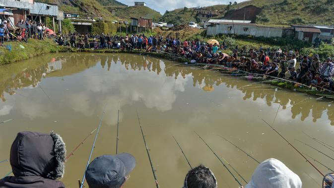 Para peserta pria berkonsentrasi dengan kailnya pada kompetisi memancing di sebuah kolam dekat desa Weilei di Negara Bagian Meghalaya, timur laut India, Sabtu (21/9/2019). Ratusan peserta berpartisipasi dalam kompetisi yang memperebutkan sejumlah hadia tersebut. (DIPTENDU DUTTA / AFP)