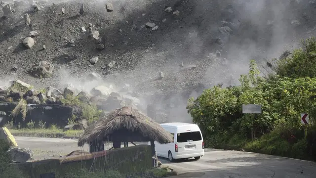 Batu-batu besar berjatuhan saat kendaraan melewati jalan selama gempa bumi di Bauko, Filipina pada Rabu 27 Juli 2022. (AP Photo/Harley Palangchao)