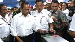 Menhub Budi Karya Sumadi menempelkan e-tiket pada reader gate sebelum naik KRL di Stasiun Juanda, Jakarta, Rabu (10/8). Menhub Budi meninjau proyek pembangunan kereta bandara Soekarno Hatta yang akan terintegrasi dari Jakarta. (Liputan6.com/Angga Yuniar)